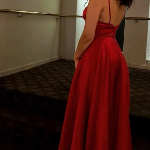 Röd balklänning  - En röd balklänning/festklänning. Använde den på min bal och har ingen användning för den längre. Släpar på mig (170 cm(klack)Modellen gör så att man inte behöver oroa sig över små detaljer under klänningen då den är lös nertill. Priset kan diskuteras