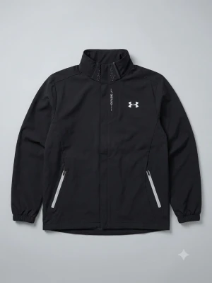 Svart vindjacka från Under Armour - Snygg svart vindjacka från Under Armour med hög krage, dragkedja och två fickor med reflekterande detaljer. Jackan har meshfoder på insidan för extra ventilation och elastiska muddar vid ärmsluten. Perfekt för blåsiga dagar och sportiga outfits. Använd ett par gånger. 