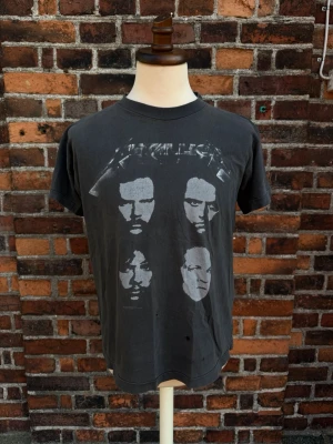 Vintage Metallica T-shirt – Europe Tour 1993 – Brockum – Large - Original licensierad Metallica T-shirt med klassiskt fyrporträtt fram och Europe Tour-tryck bak. Copyright ©1993 Metallica. Snygg vintagefade och dubbelsidigt tryck.  • Storlek: L • Armhåla–armhåla: 55cm • Längd: 69cm • 100 % bomull  Tröjan har flera mindre hål framtill (se bilder), vilket ger en naturlig vintage/distressed look. Perfekt för samlare eller dig som gillar äkta 90-talsbandtröjor.