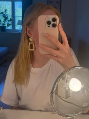 Stora guldiga statementörhängen - Säljer ett par stora statementörhängen i guld med unik, hamrad textur. Örhängena har en rund del upptill och en rektangulär, öppen del nedtill. Perfekta för dig som vill sticka ut och addera lite extra till din look. Örhängena är inte äkta guld.