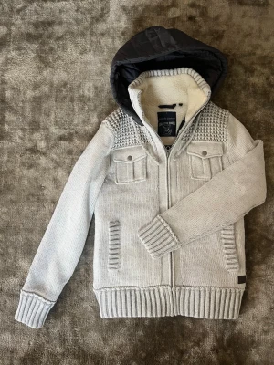 Ljusgrå stickad cardigan med huva - Ljusgrå stickad cardiganjacka från Angelo Litrico med dragkedja, två bröstfickor med lock och två sidofickor. Jackan har en  svart huva i quiltat material och mjukt foder i kragen. Snygga stickade detaljer på axlarna och ribbade muddar. Om du har frågar är det bara att fråga på. Pris går att diskutera med seriösa köpare. Kolla in min profil och se om du hittar något mer intressant. Mvh Larsen_Closet