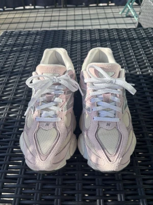 New Balance rosa och vita sneakers - Säljer ett par snygga New Balance sneakers i ljusrosa och vitt. Skorna har meshpaneler för bra ventilation och detaljer i mocka. Klassisk N-logga på sidan och vita skosnören. Perfekta för dig som gillar sportig och trendig stil.