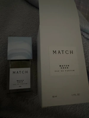 Match Coco Eau de Parfum 50ml - Match Coco Eau de Parfum är en stilren parfym i en transparent glasflaska med vit etikett och ljusblått lock. Flaskan rymmer 50 ml och har en modern, minimalistisk design. Perfekt för dig som gillar fräscha och eleganta dofter.