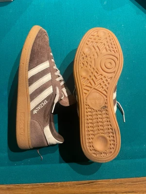 Adidas Spezial sneakers mocka brun/vit - Säljer ett par Adidas Spezial sneakers i brun mocka med vita detaljer och klassiska tre ränder på sidan. Skorna har vit snörning och gummisula i beige. Perfekta för dig som gillar retrostil och streetwear.