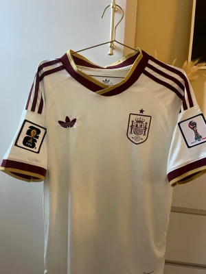 Spanien borta tröja - Säljer en officiell bortatröja för Spaniens landslag, komplett med VM-emblem på ärmen/bröstet. Tröjan är i absolut nyskick då den endast är provad en snabb gång. 