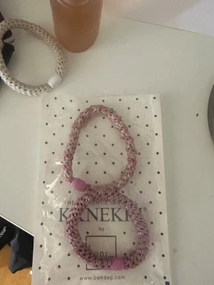 Två rosa glittriga hårsnoddar - Två stycken tjocka hårsnoddar i olika nyanser av rosa med inslag av glitter. Snoddarna är spiralformade och har plastdetaljer i ändarna. Perfekta för att sätta upp håret med en snygg touch.