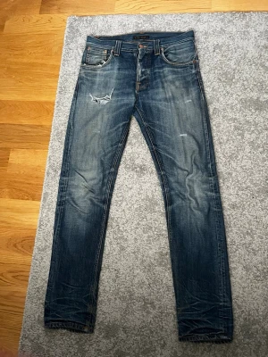 Nudie Steady Eddie 30/34 - Nudie Steady Eddie 30/34. En av dem snyggaste tvättarna jag sett. Lite slitningar här och där som verkligen ger jeansen än vintage look. OBS litet hål i högra fickan. Kan sätta telefonen där utan problem men kan lämnas in på nudie affär och få lagat lagas själv. Jeansens tvätt och perfekta passform ger jeansen högt värde.