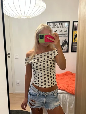 Prickig topp i svart och vit - Vit topp med svarta prickar perfekt på fest eller under sommaren!🤍🖤 Går att välja själv hur den ska sitta, t.ex. off shoulder. Toppen är croppad och har en figurnära passform. Superskönt material, toppen är i polyester. Använd fåtal gånger.