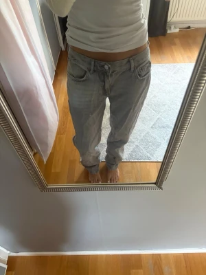 Baggy ljusgråa jeans - Säljer ett par ljusgråa baggy jeans med rak passform och låg midja. Jeansen har klassiska fem fickor och är tillverkade i denim. Perfekta för en avslappnad och trendig look.