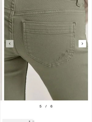 Olivgröna bootcut jeans - Snygga olivgröna jeans med bootcut-passform och klassiska fickor bak. Jeansen har en stilren look med diskret broderi på bakfickan och är tillverkade i ett mjukt bomullsmaterial med lite stretch för extra komfort.
