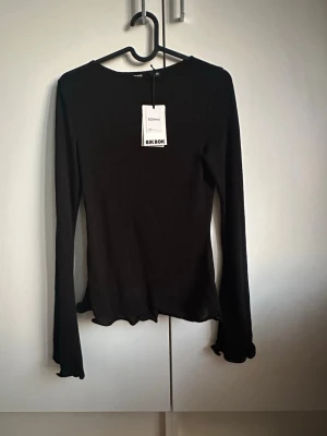 Svart långärmad topp - Snygg långärmad, lite tunnare, topp med vågiga kanter. Oanvänd. Nypris 259kr