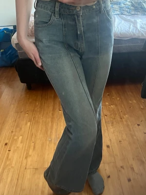 Blå bootcut jeans med hög midja - Säljer ett par blå bootcut jeans med hög midja. Jeansen har en  markerad söm framtill och är tillverkade i denim. Passar bra om du gillar retrostil.  En sak bra att veta är att jeansen är insydda, var från början S och nu mer xs. De är en aning noppriga också. 