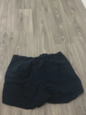Mörkblåa  shorts med dragkedja - Säljer ett par svarta shorts med dragkedja och ingen knapp. Shortsen har en enkel design med fickor på sidorna och elastisk midja baktill. Perfekta för varma dagar och lätta att matcha med olika stilar.