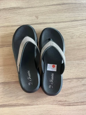 Svarta sandaler med glittriga band -  Flip flops aldrig de använda. nypris 200kr