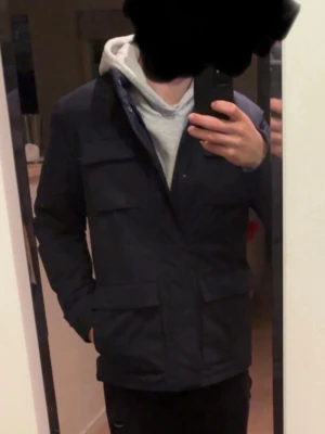 Field jacket John henric - Stilren vadderad field jacket i mörkblå från John Henric. Använd ett fåtal gånger. Jackan har Snörning i midjan och dubbeldragkedja. Perfekt för dig som vill ha en avslappnad stil.