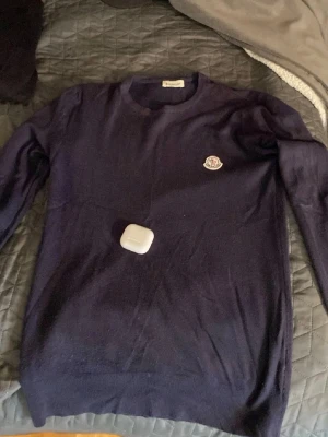 Mörkblå stickad tröja från Moncler - Snygg mörkblå stickad tröja från Moncler med rund halsringning och Moncler-logga broderad på bröstet. Tröjan har en klassisk passform och är perfekt för dig som gillar stilrena plagg med exklusiv känsla.