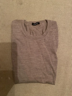 Beige tunn stickad tröja - En stilren, tunnstickad tröja i beige med rund hals och långa ärmar. Tröjan har en enkel design utan mönster och är gjord i ett mjukt material som passar perfekt till lager på lager. Perfekt för dig som gillar minimalistisk stil. Tröjan är gjord av 100% cashmire. Tveka inte på att höra av dig! Mvh Sam