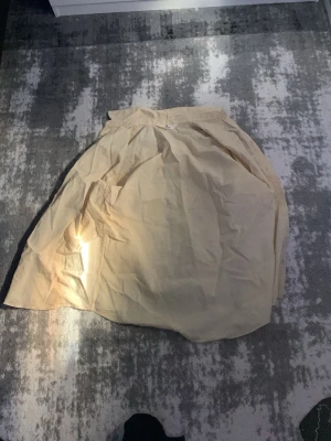 Beige långkjol i bomull - Säljer en beige långkjol med hög midja och enkel, klassisk design. Kjolen är gjord i ett tunt bomullstyg som ger en luftig känsla och passar perfekt till varmare dagar. Den har en rak och avslappnad passform.