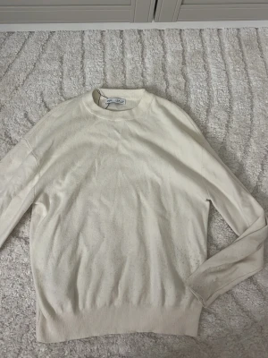 Vit stickad tröja från Zara - Snygg vit stickad tröja från Zara i storlek 164. Tröjan har rund halsringning, långa ärmar och ribbade muddar vid ärmslut och nederkant. Perfekt för dig som gillar en clean och enkel stil.
