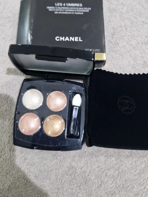 Chanel ögonskuggspalett neutrala toner - Snygg ögonskuggspalett från Chanel med fyra skimrande nyanser i guld, champagne, koppar och beige. Kommer i en elegant svart dosa med spegel och applikator samt tillhörande sammetsfodral. Perfekt för att skapa både mjuka och intensiva ögonlooks.