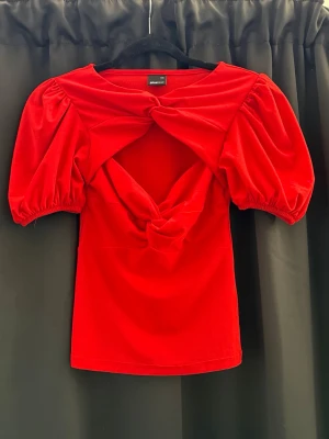 Röd topp stl xxs - Fin röd topp med puffiga korta ärmar och snygga knyt-detaljer framtill. 