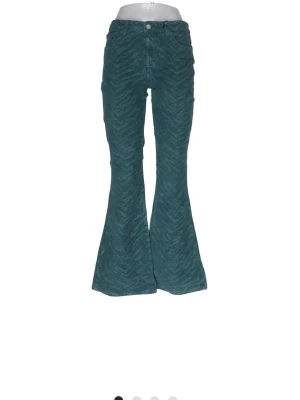 Blågröna bootcut jeans med mönster - Säljer ett par blågröna bootcut jeans med diskret zebramönster. Jeansen har hög midja, klassisk femficksmodell och vida ben som ger en retrovibe. Perfekta för dig som vill sticka ut lite extra med coola detaljer.