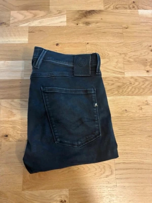 Replay jeans - Säljer ett par svarta slim fit jeans med klassisk femficksdesign och svarta sömmar. Jeansen har en diskret logga på bakfickan och är tillverkade i stretchigt material för extra komfort. Perfekta för dig som gillar en smalare passform.