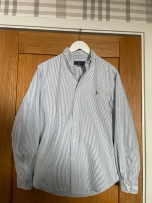 Blårandig skjorta från Ralph Lauren M slim fit - Klassisk blårandig skjorta från Ralph Lauren i slim fit-modell, storlek M. Sparsamt använd och i väldigt gott skick