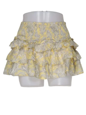 Gul volangkjol med blommönster - Söt kort kjol i gult med volanger och blommigt mönster. Kjolen har bred smock i midjan för skön passform och är gjord i ett lätt bomullstyg. Perfekt för varma dagar och ger en lekfull vibe till din outfit.