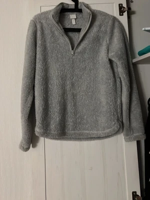 Ljusblå fleece tröja med dragkedja - Ljusblå fleece tröja i fluffigt material med halv dragkedja och hög krage. Tröjan har lång ärm och en avslappnad passform som ger en cozy känsla. Perfekt för lager-på-lager och för dig som gillar mjuka plagg.