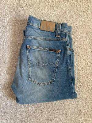 Nudie Jeans Grim Tim - 32/32 - Snygga Nudie Jeans i den populäraste modellen Grim Tim i färgen Indigo Blench.  Storlek: W32 L32 Modell: Grim Tim Färg: Indigo Blench Skick: Mycket gott skick  Jeansen är väldigt sparsamt använda och fina med mycket snygg tvätt och detaljer. Se bilder för skick och färg.  📦 Skickas snabbt! 💬 Skriv vid funderingar!