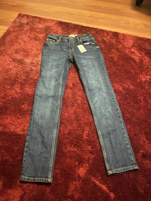 Blå slim fit jeans från 157 - Snygga blå slim fit jeans från 157 med klassisk femficksdesign och kontrastsömmar. Modellen heter Slimmy Star och har raka ben med smal passform. Perfekta för dig som gillar en enkel och stilren look. 