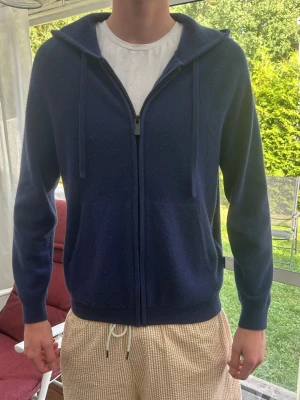 Mörkblå Kashmir zip hoodie - Mysig mörkblå hoodie med dragkedja från Ecoalf. Tillverkad av 70% återvunnen ull och 30% återvunnen kashmir. Klassisk modell med huva och ribbade muddar. Perfekt för en chill och stilren look. Är nästan oanvänd 10/10 skick