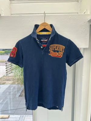  Superdry piké  - Snygg marinblå Superdry piké i fint skick. 
