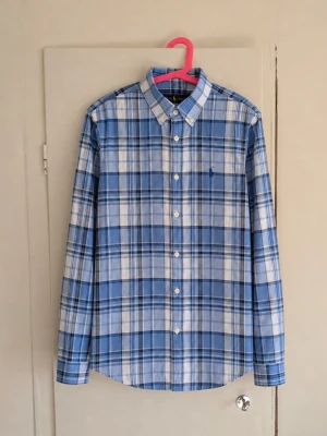 Polo Ralph Lauren rutig skjorta 💙 - Klassisk rutig skjorta från Polo Ralph Lauren i blått, vitt och marinblått. Snygg button-down-krage och den ikoniska broderade Ralph Lauren-loggan på bröstet. Tidlös/preppy modell som passar lika bra till jeans som chinos. Storlek: L (14-16) Skick: Fint skick, den har inga defekter✨ Skriv gärna om du vill ha mått eller fler bilder!