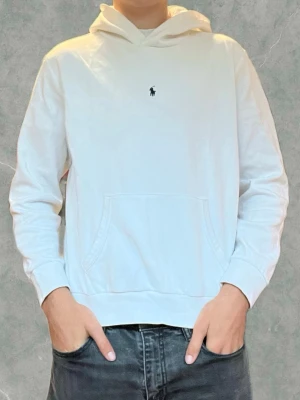 Vit Ralph Lauren hoodie  - Säljer en stilren vit hoodie från Polo Ralph Lauren med den klassiska broderade loggan på bröstet. Den är i toppen skick förutom den pyttelilla defekten ni kan se på sista bilden som knappt märks. Storlek 18/20 barnstorlek vilket motsvarar en S. Vid några frågor eller funderingar är det bara att höra av sig.