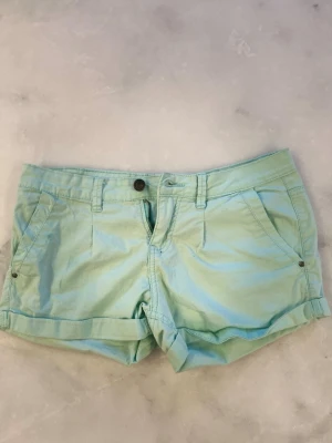 Ljusgröna shorts från Inside - Snygga ljusgröna shorts från Inside med klassisk femficksdesign, uppvikta benslut och bälteshällor. Tillverkade i mjuk bomull som passar perfekt till varma dagar. Stängs med knapp och dragkedja framtill.