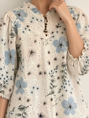 Blommig blus med knappar och volang - Söt blus vit med blå och rosa blommor, volangkrage och dekorativa knappar framtill. Blusen har trekvartsärm med resår vid ärmslut och är tillverkad i ett lätt, luftigt tyg. Perfekt för en trendig och avslappnad look.