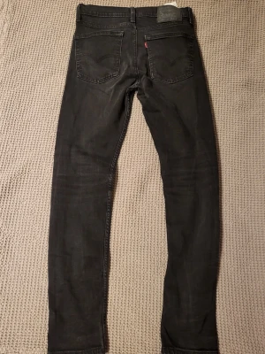 Svarta skinny jeans från Levi's med fem fickor - Snygga svarta Levi's skinny jeans med klassisk femficksdesign och smal passform. Jeansen har bälteshällor, knappgylf och subtila slitningar för en trendig look. Perfekta till sneakers eller boots och passar till många olika stilar.