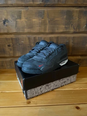 Svarta Nike Air Jordan sneakers - Snygga svarta Nike Air Jordan sneakers med lågt skaft och diskreta detaljer. Skorna har en liten röd swoosh på sidan, vit AIR-text på hälen och en synlig luftbubbla i sulan. Tillverkade i mocka och textil för en clean och sportig look. Bara att höra av sig om du har någon fråga.