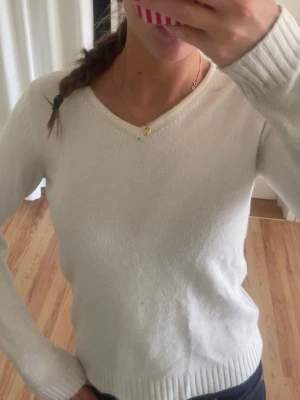 Vit stickad tröja från VILA - Klassisk vit stickad tröja från VILA med v-ringning och långa ärmar. Tröjan har ribbade muddar vid ärmslut och nederkant, vilket ger en snygg och enkel look. Perfekt att matcha med jeans eller kjol för en clean stil.