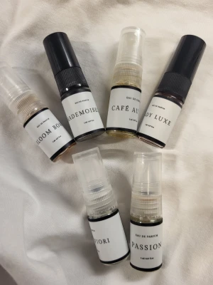Set med 6 parfymprover i sprayflaskor - Säljer ett set med 6 olika parfymprover i små genomskinliga plastflaskor med sprayfunktion. Varje flaska har en vit etikett med svart text och olika namn som Bloom Bou, Mademoiselle, Café Au, Lady Luxe, Fiori och Passion. Perfekt för att testa nya dofter.💕💋