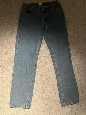 Blå raka jeans med hög midja - Säljer ett par klassiska blå jeans från grunt. Jeansen har fem fickor och stängs med knapp och dragkedja. Perfekta till en avslappnad stil och passar till det mesta. Materialet är kraftigt denim i bomull. Dem är lagom baggi och ass sköna! säljer för 250 kr men kan med på priser ner till 150 kr möjligtvis! Skicket är väldigt bra då dem inte är använda så mycket! Rekommenderar att kolla in mina andra jeans i min profil som då också är andra färger ifall du söker det!