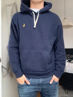 Mörkblå Ralph lauren hoodie  - Snygg mörkblå hoodie från Polo Ralph Lauren med gul broderad logga på bröstet. Perfekt för en avslappnad och stilren look. Kan används till vad som, en chill kväll, ute o gå, skolan, ica rush, chill med kompisar eller vad som!!