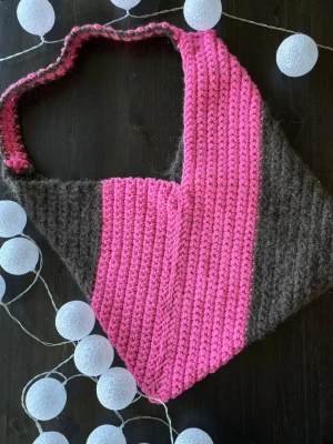 Stickad shoppingväska rosa och brun - Unik handstickad shoppingväska i chunky garn med breda ränder i stark rosa och mörkbrunt. Det röda garnet har även reflex i sig. Väskan har en mjuk struktur och ett brett axelband, perfekt för att bära dina grejer med stil. Materialet är tjockt och mysigt, vilket ger en cool och personlig look.  Måtten på väskan är 37 cm bred och 42 cm hög 🌸