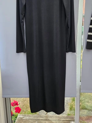 Svart långärmad långklänning helt ny m.lapp från lager157 storl.XL - En stilren svart långklänning med lång ärm och rak passform. Klänningen har en enkel design utan synliga detaljer och är tillverkad i ett mjukt, stretchigt material som ger en bekväm känsla.