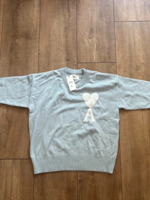 Helt ny Ami Paris Oversized Jumper (Ljusblå/Vit) - Strl S 🔥✨ - Säljer en superfresh och helt ny Ami Paris-tröja i en snygg ljusblå nyans med den klassiska stora Ami de Coeur-loggan i vit chenille. Aldrig använd, tags och originalpåse medföljer!  Storlek: S (Oversized fit)  Skick: Helt ny / Deadstock (DS) med tags  Färg: Ljusblå / Vit  Kvitto: Saknas Skickas spårbart eller hämtas enligt överenskommelse. Köparen står för frakten. Skriv ett DM om du har några frågor eller vill ha fler bilder! 👕✨ 