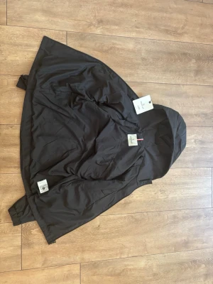 Moncler Vindjacka / Regnjacka Svart - Storlek M - Snygg svart Moncler-jacka i storlek M. Använd ett fåtal gånger och är i väldigt fint skick utan slitage. Stilren modell med luva och Moncler-logga på ärmen samt dragkedja framtill.  Skick: Fint skick (använd få ggr)  Storlek: M  Färg: Svart  Kvitto: Finns ej 