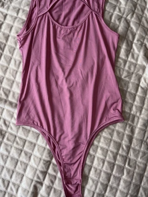Rosa ärmlös body i stretchigt tyg - Säljer en snygg rosa body med ärmlös design och rund halsringning. Tillverkad i ett mjukt och stretchigt material som sitter skönt mot kroppen. Perfekt att styla med jeans eller kjol för en trendig look. Från SHEIN o aldrig använt. 