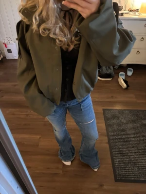 Blå bootcut jeans med slitningar - Säljer ett par ljusblå bootcut jeans med slitningar på knäna och lätt tvättad look. Jeansen har klassisk femficksmodell och är tillverkade i denim med lite stretch. Perfekta för en avslappnad och trendig stil.